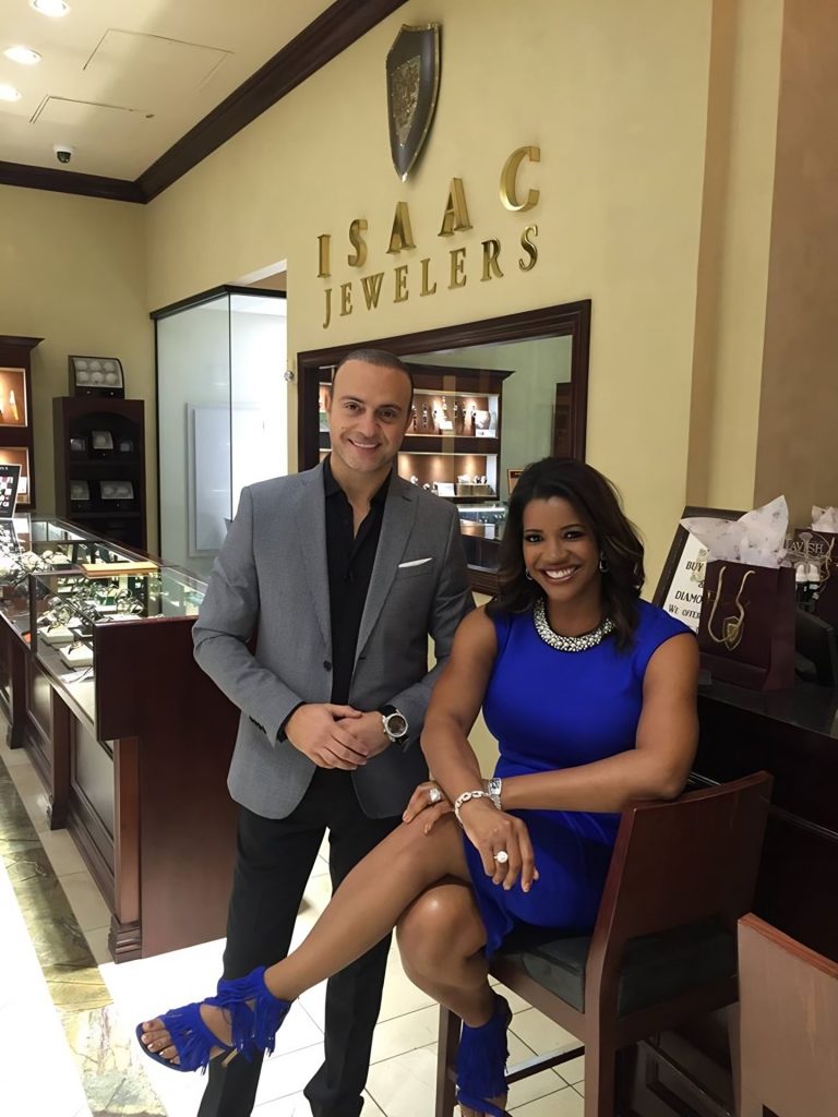 Frank Isaac with a guest beneath the Isaac Jewelers sign inside the store