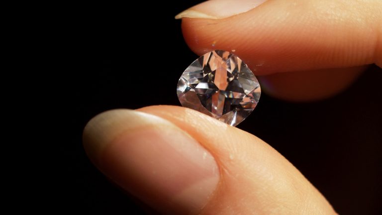 A cushion-cut diamond held up between two fingers