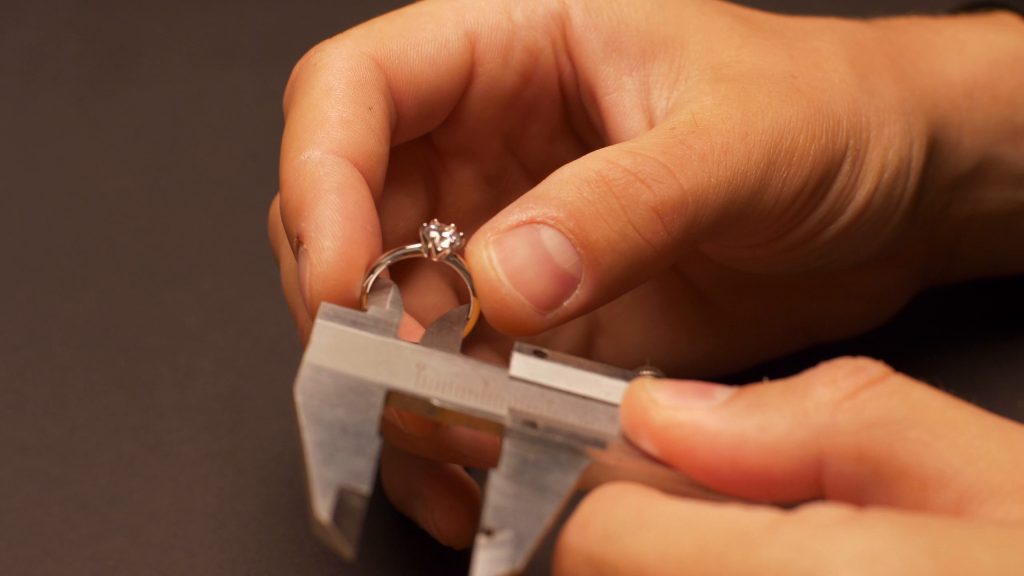 A diamond ring being measured with a caliper