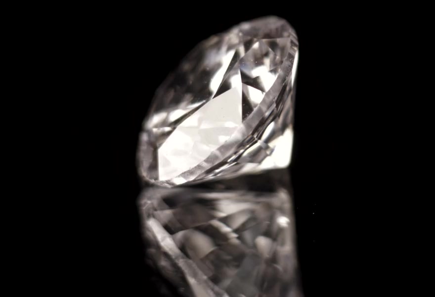 A brilliant-cut diamond turning on black glass