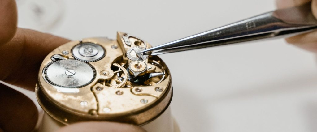 A watch movement being serviced with tweezers